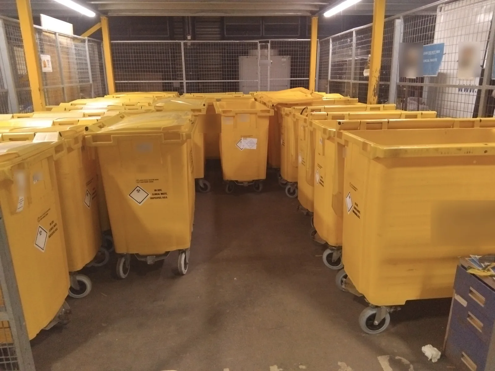 Rows of yellow clinical waste bins in a secure compound collected by Red Eagle Logistics clinical waste transport