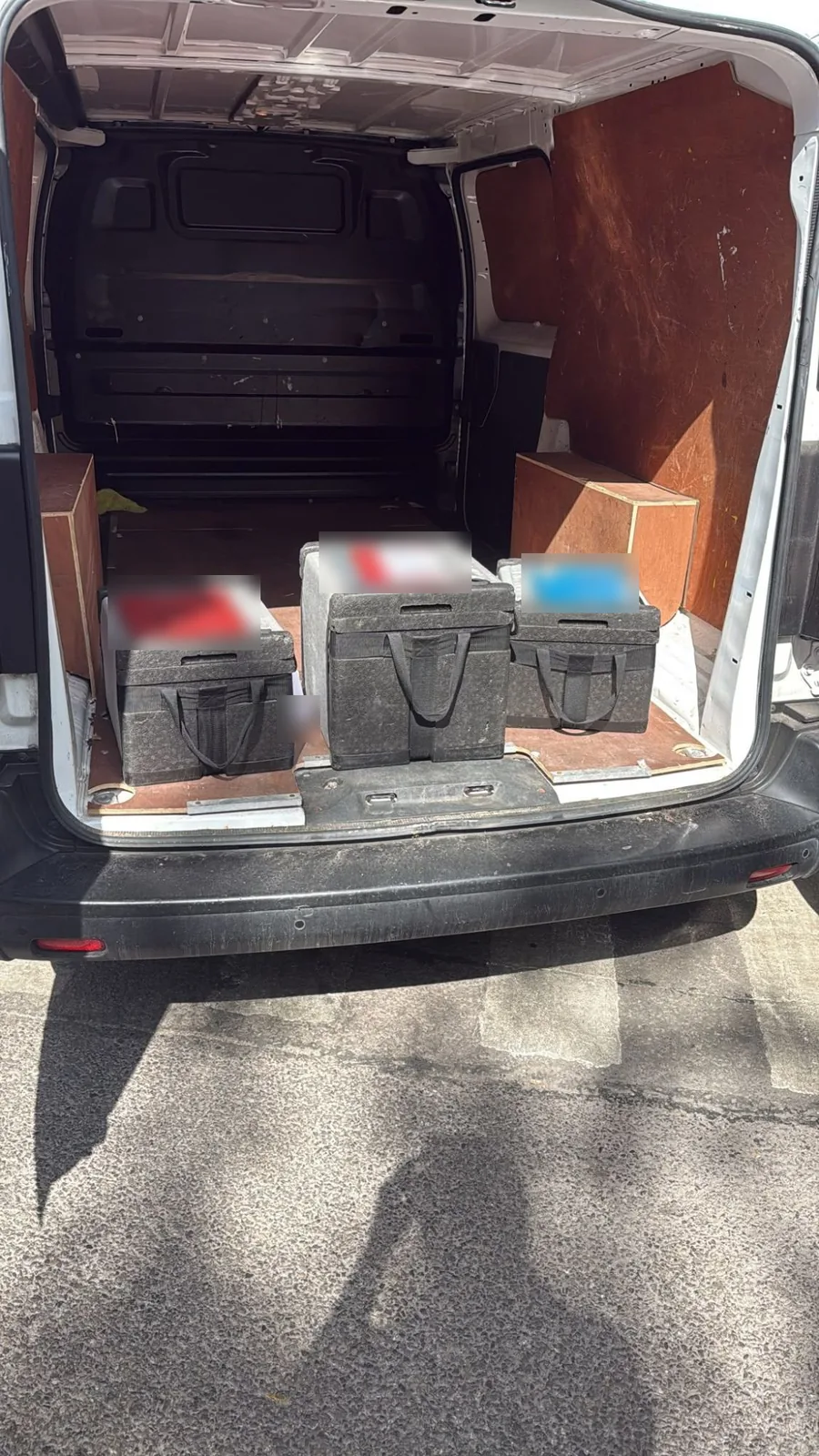 Three insulated transport boxes loaded in a Red Eagle Logistics van for a pathology sample run
