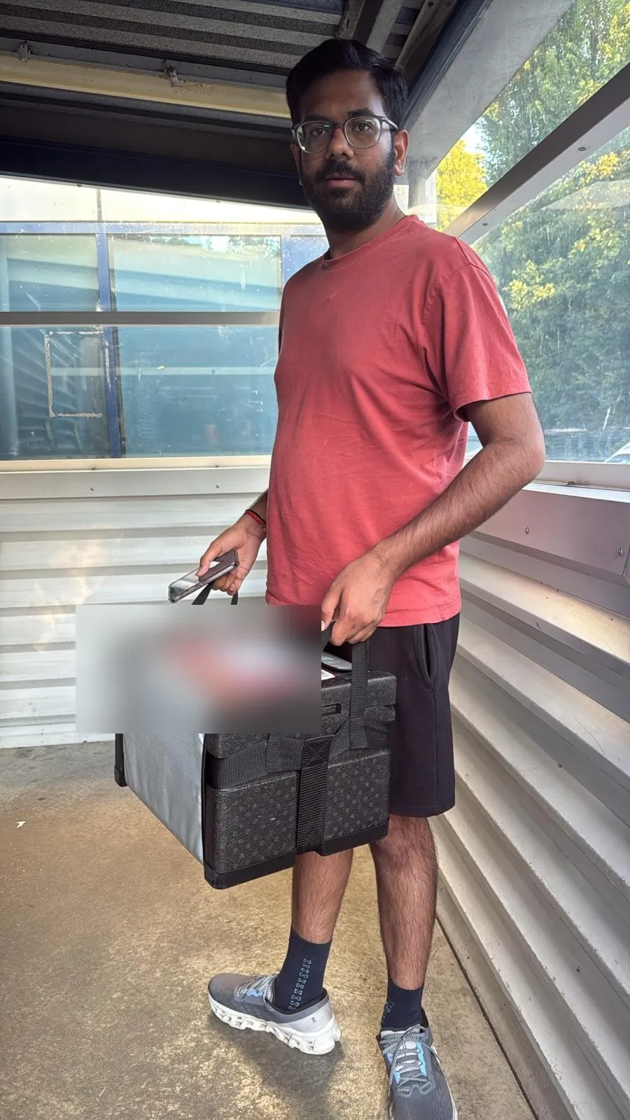 Red Eagle Logistics courier driver carrying an insulated medical delivery box on a same-day collection